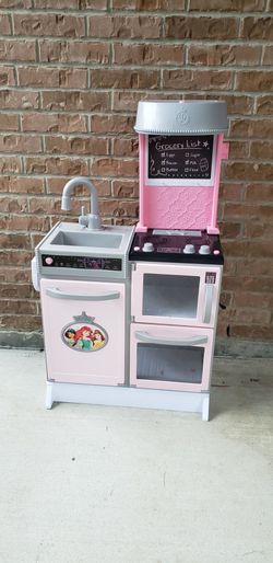 The Disney Princess Style Collection Gourmet Smart Kitchen is a pink and grey play set featuring interactive appliances like a stove, oven, and refrig