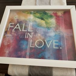 19 By 22.5 Inches Framed Artwork W/ Saying Fall In Love, White Thick Plastic Frame, Clear Cover Has Saying Floating Over Color Background 