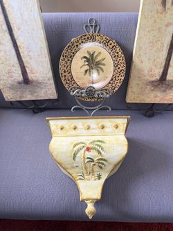 Palm tree themed wall art including two panels, a decorative plate, and a wall sconce.