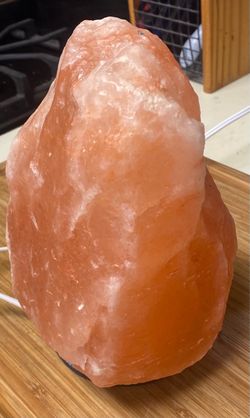 This glowing natural Himalayan salt lamp features a rough-hewn pink crystal block mounted on a decorative circular