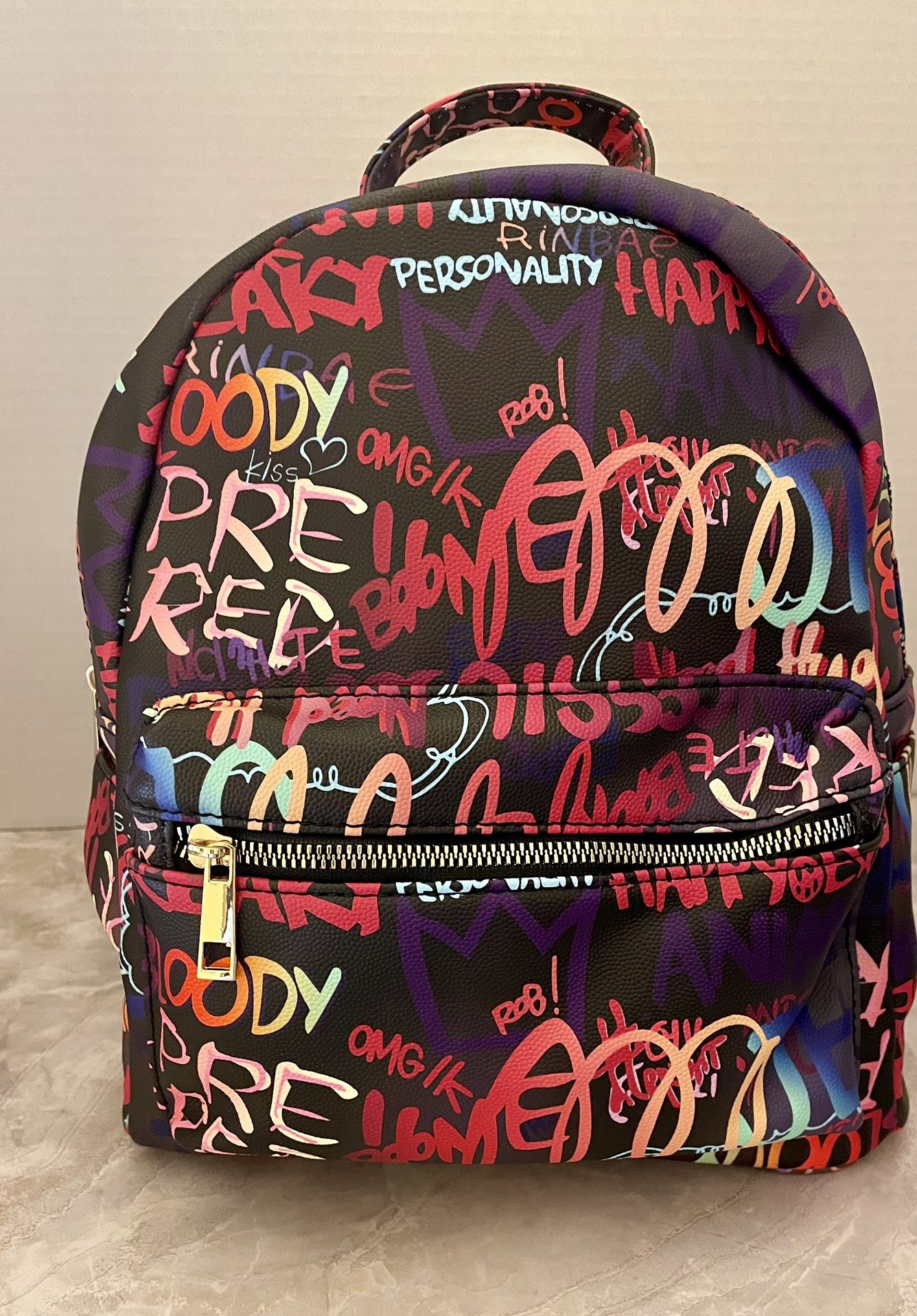 Multi Graffiti Backpack. Faux Vegan Leather. Gold Tone Hardware. Zip Top Closure