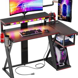 Gaming Desk with Music Sync Light, Flow Vibe L-Shaped Gaming Desk with Monitor Stand and PS5 Storage Shelves, Cup Holders, and Headset Hooks (Black Pu