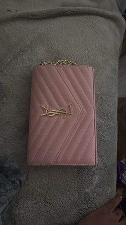 Saint Laurent (YSL) envelope-style crossbody bag in a dusty rose or mauve color, with a gold-tone YSL logo and chain strap