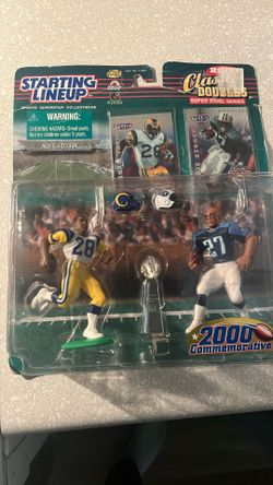 This product is a "Starting Lineup 2000 Classic Doubles" action figure set featuring NFL players Marshall Faulk and Eddie George. This commemorative s
