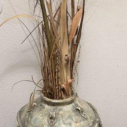 Large decorative vase with metal accents and dried plants.
