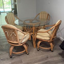 Glass top 42 inch table with bamboo chairs on wheels… thick cushions. $175 Delivery available for a small fee 