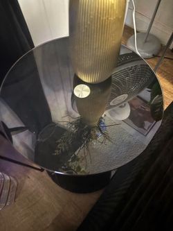 A used velvet futon couch and black glass end tables and coffee table