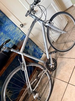 This is a silver Specialized Sirrus hybrid fitness bicycle featuring an aluminum frame and a triple crankset.