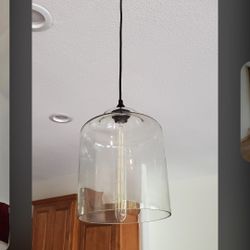 Large clear glass globe pendant lights with black cords and metal finish