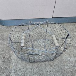 Rustic wire basket, oval shape. Has wood handles. Great for decor, garden stuff, or just holding things. About 15 inches long and 10 inches wide. Pret