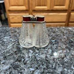 Vintage Mid century glass pair of salt and pepper shakers with holder with Red Bakelite lids. Preowned the metal is a little rusted due to age.