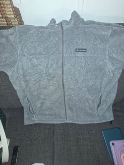 Soft Columbia fleece jacket in heather gray. This garment is a full-zip model with a stand-up collar and two zippered hand pockets. The material is a 