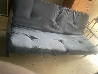 This modern blue futon features a tufted mattress and a sleek black metal frame.