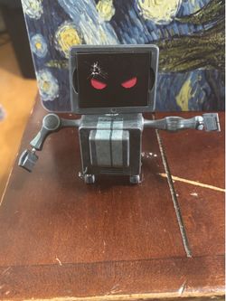 grey robotic toy figure with a screen for a face displaying red eyes and a cracked appearance