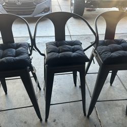 Three metal stool chairs with cushions