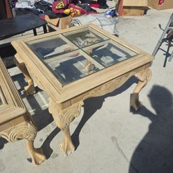 wooden coffee table features carved legs with a light finish and a multi-pane glass top. 