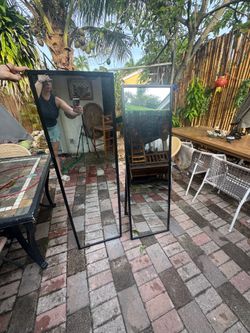 Two black framed full length floor mirrors