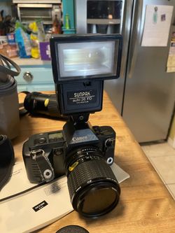 Vintage 35mm Canon T70 film camera with lenses and flash