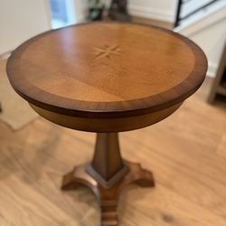 Inlaid wood top with a starburst or compass rose design.