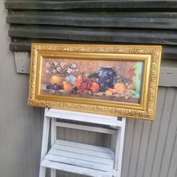 A framed still life painting of fruit and vases by Nancy Wiseman.