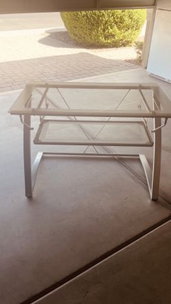 Modern glass-top computer desk with a curved silver metal frame and a pull-out keyboard tray.