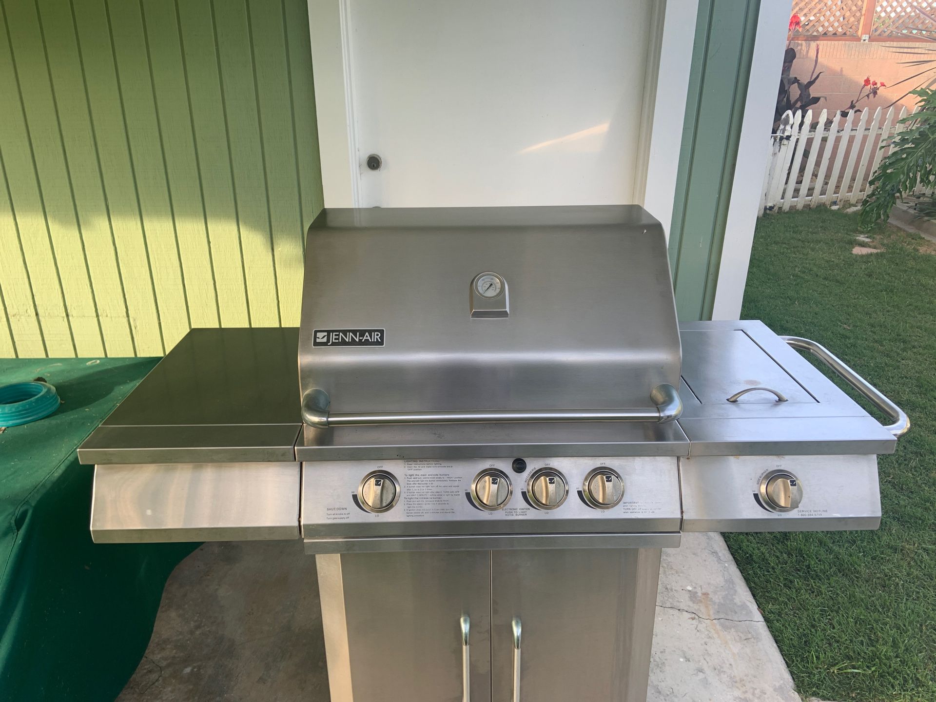 Stainless steal JennAir BBQ with stainless grills and a canvas cover