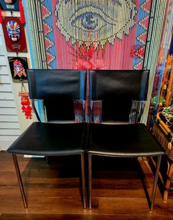 Italian postmodern chairs feature black leather upholstery  chrome steel frames. Set of 2