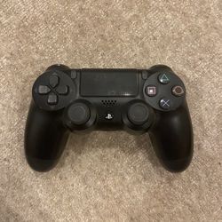 Black PS4 DualShock controller with classic buttons, touchpad, and analog sticks.