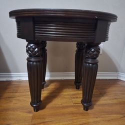 Oval wood accent table with fluted legs and a pineapple motif