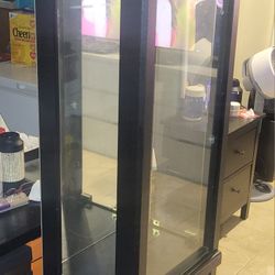 This is a black wooden and glass curio display cabinet. 
