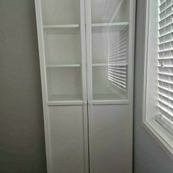 Tall white cabinet with glass doors and shelves.
Ikea Bookcase with panel glass doors 
31.5 × 11.75  × 79.5 "