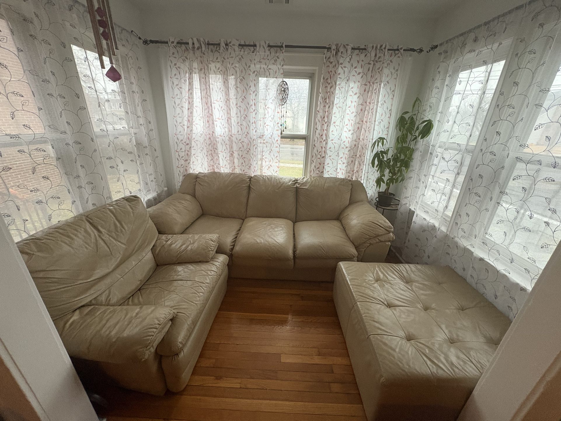 The set features a beige leather couch, a Center Cushion and matching reclining chair. 