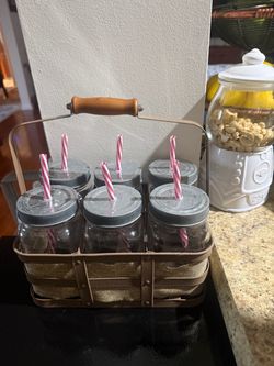 Six mason jar drinking glasses with metal lids, striped straws, and a matching carrier. They have never been used for drinks and were only displayed.