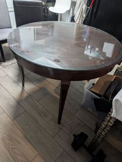 traditional round mahogany dining or accent table featuring a protective custom-cut glass top