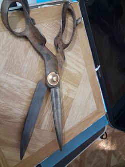 a pair of vintage metal shears or scissors that are currently in a rusted condition. These items feature a brass-colored pivot bolt embossed with the 