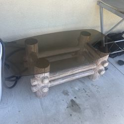 rustic coffee table featuring a log-style base made from cedar or pine logs and a tinted glass top