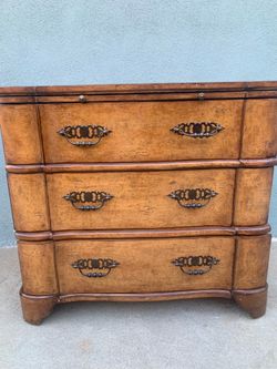A French Provincial style three-drawer bombe chest with ornate brass hardware.