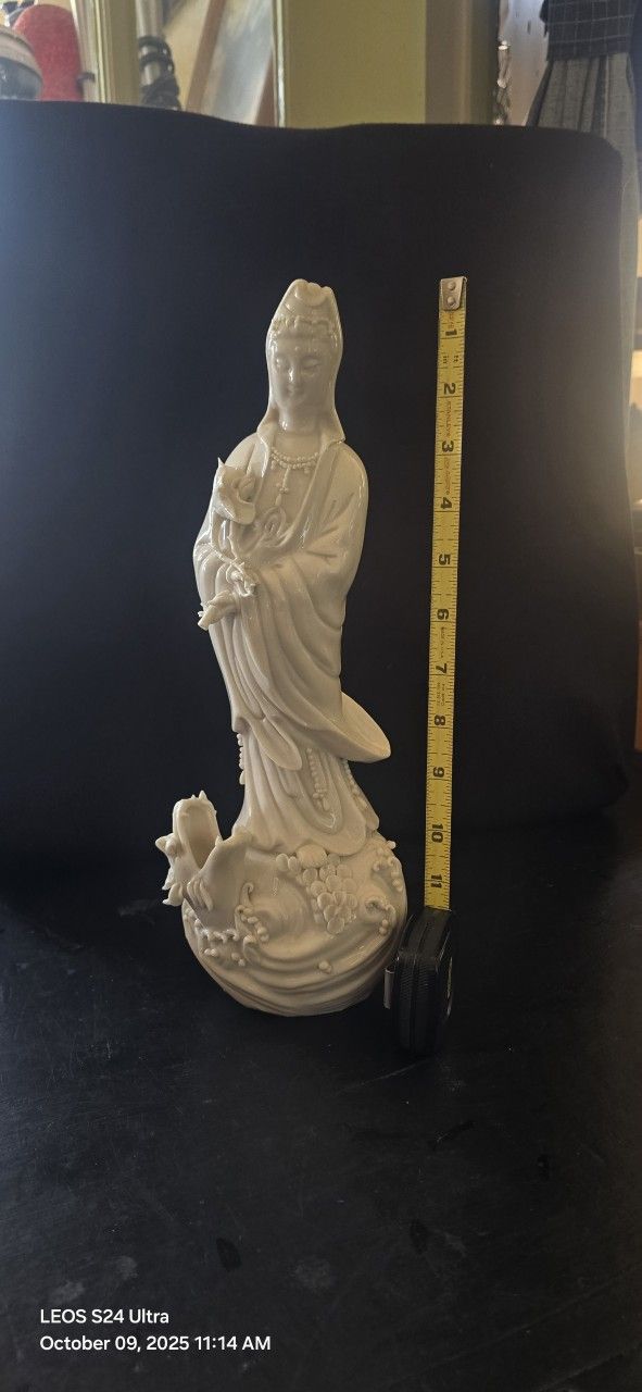 The statue is a Blanc de Chine porcelain figurine of Guanyin (also known as Kwan Yin), the Buddhist Bodhisattva of
