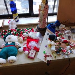  of Christmas decorations and collectible items, including plush toys, ornaments, and a statue, on a windowsill. 