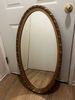 vintage Hollywood Regency-style gold oval mirror with floral trim