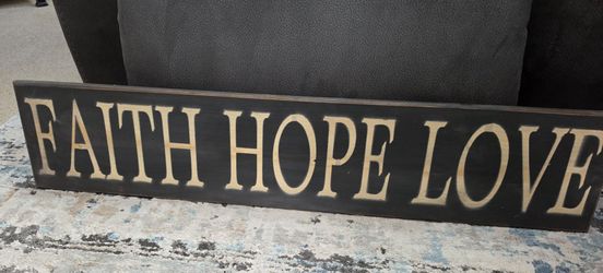 wooden wall plaque features the phrase "FAITH HOPE LOVE," a popular inspirational quote