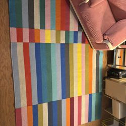 Pink Suede Chair With Matching Ottoman And Rainbow Checkered Rug 