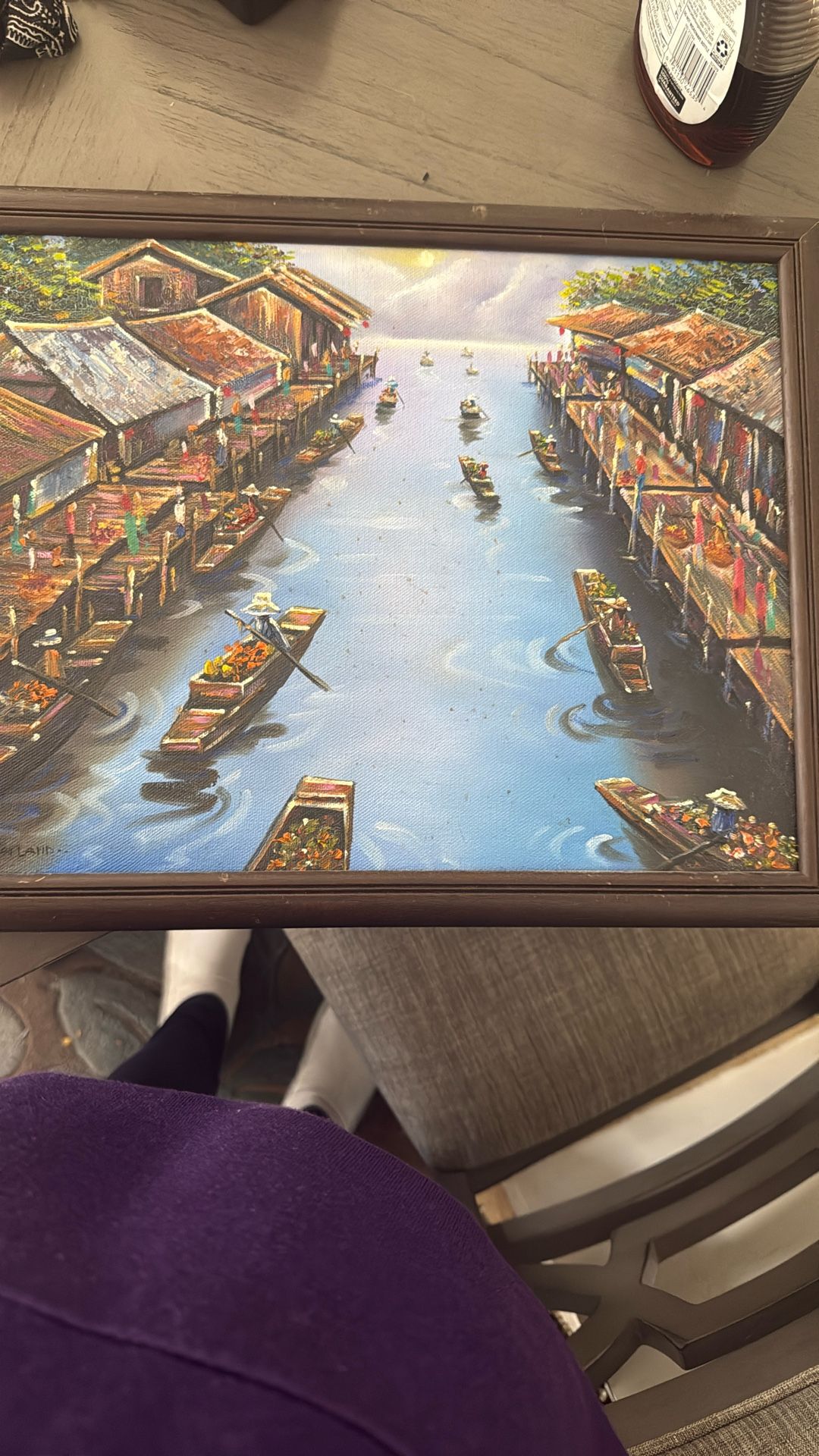 This painting depicts a bustling riverside village at dusk where small boats filled with produce float along a calm waterway. Wooden stilt houses lin