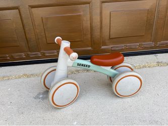 SEREED baby balance bike features a distinctive sage green frame and brown cushioned seat.