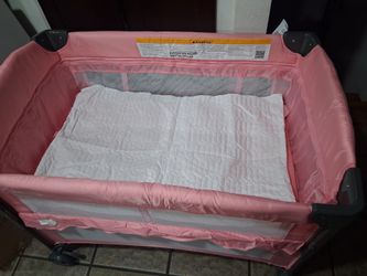 Baby beside bassinet pink