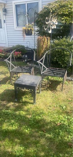 The composition in the garden features two chairs and a table made of iron.