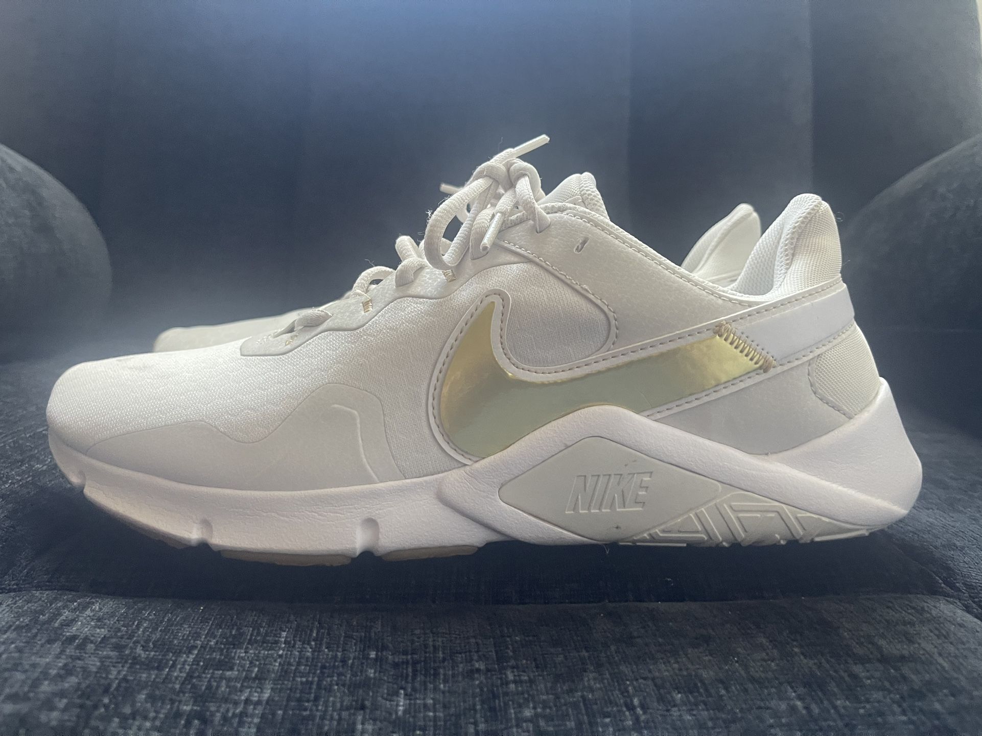 Size 12 Nike Women's Legend Essential 2 training sneakers in white and gold.