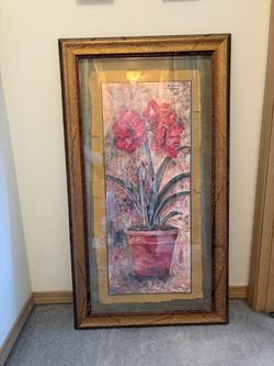 41”tall x 23” wide Elegant framed wall art depicts red amaryllis flowers in a terracotta pot. The piece is set within a textured gold-tone frame and p