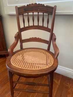A refinished Victorian armchair with carved details and a caned seat.