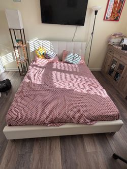 Upholstered queen bed with headboard and wooden slats.